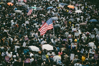 A tense protest scene with American flags and passionate crowds under a cloudy sky.