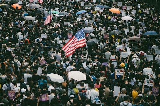 A tense protest scene with American flags and passionate crowds under a cloudy sky.