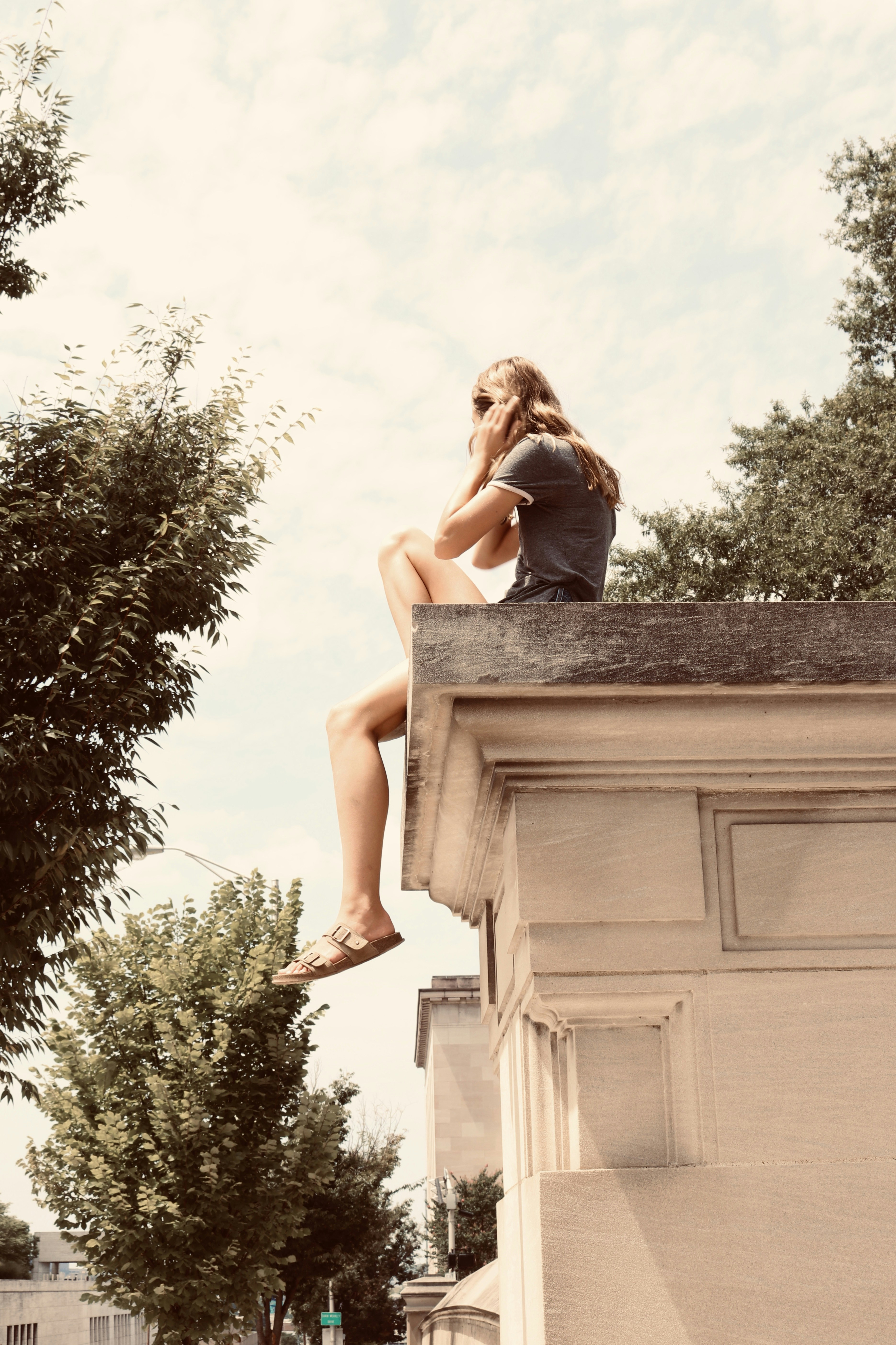 woman sitting on building roof edge during day