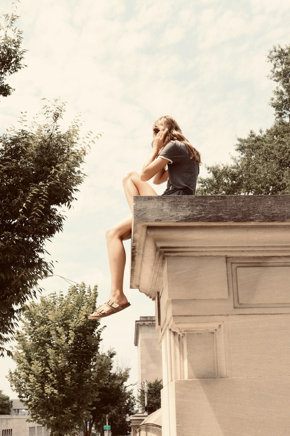 woman sitting on building roof edge during day