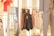 A retail store interior displaying various clothing items, including jackets and sweaters on racks. Mannequins dressed in outfits, one wearing a red shirt. Shoes are visible on the shelves in the background.