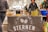 A market stall with a banner featuring the text 'Restaurant Bar Sternen' displayed. Various beverages are organized in ice buckets including a blue Ciroc bucket, and there are snacks on the table, possibly samples. People are standing around the stall in casual clothing.