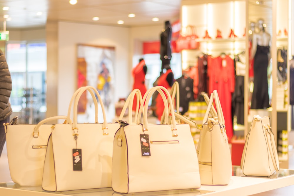 shallow focus photo of white leather handbags on table