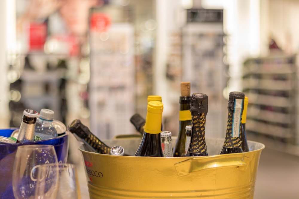 shallow focus photo of bottles on yellow steel bucket