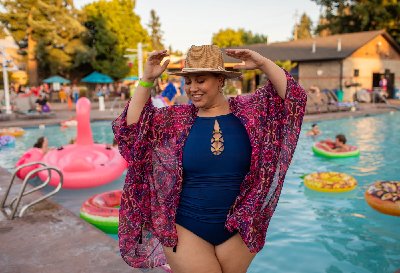 Frau in blauem Badeanzug mit rosa Tuch am Pool