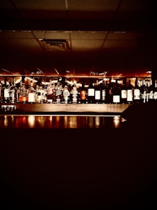 Shelves of rich bourbon, wine, and jewelry sparkling under soft purple lighting.