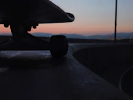 Skateboard wheels spinning fast on cracked asphalt under bright sunlight.