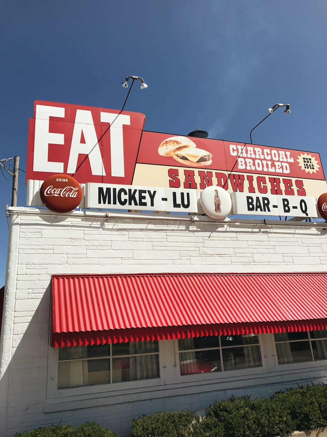 A roadside diner with bold graphic signs lines the highway in the rural UP of Michigan, a destination for vacation travelers, framed with brilliant blue skies.
