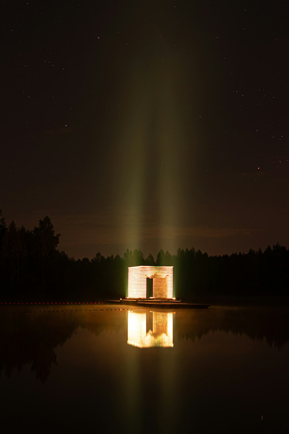 a light shines brightly in the night sky over a body of water