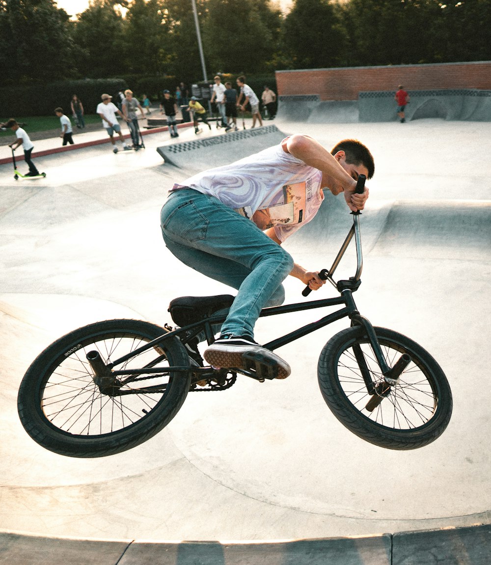 man wearing gray shirt riding BMX bicycle on air