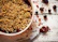 A rustic ceramic bowl filled with mixed berry crumble on a wooden table.