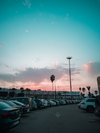 A vibrant parking lot bathed in yellow and royal blue lighting, showing neatly parked cars under clear skies.