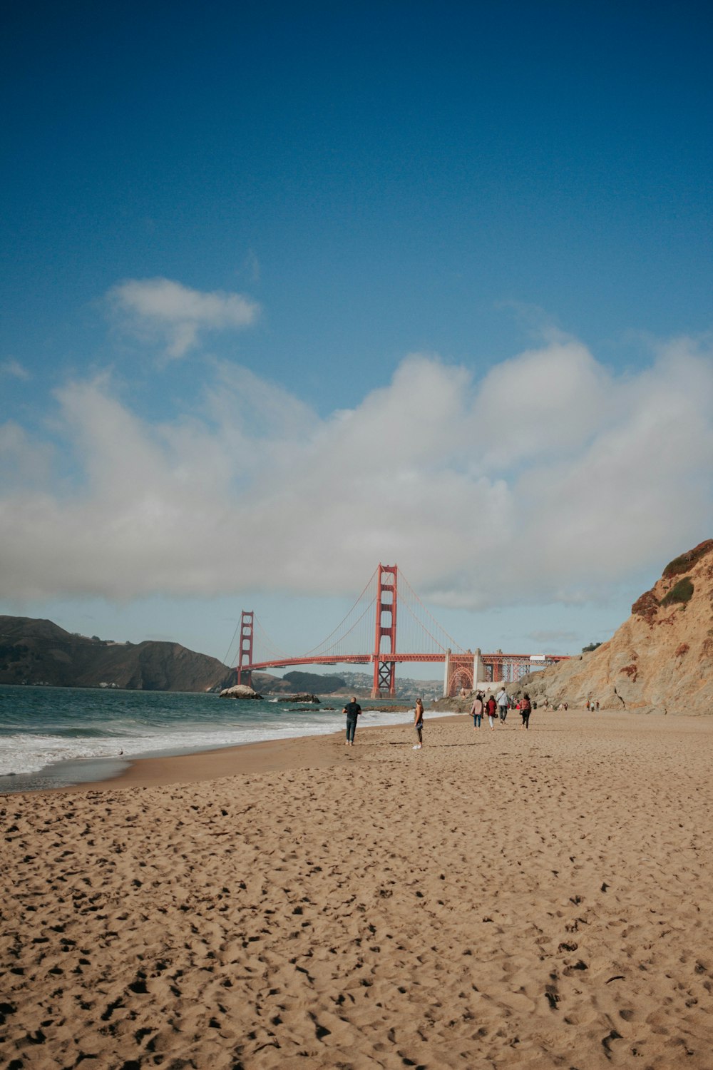 people walking on seashore near Golden Gate Bridge