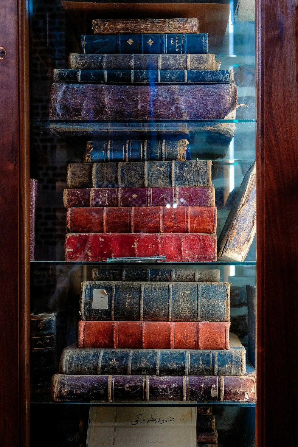 assorted books on glass panel wooden cabinet