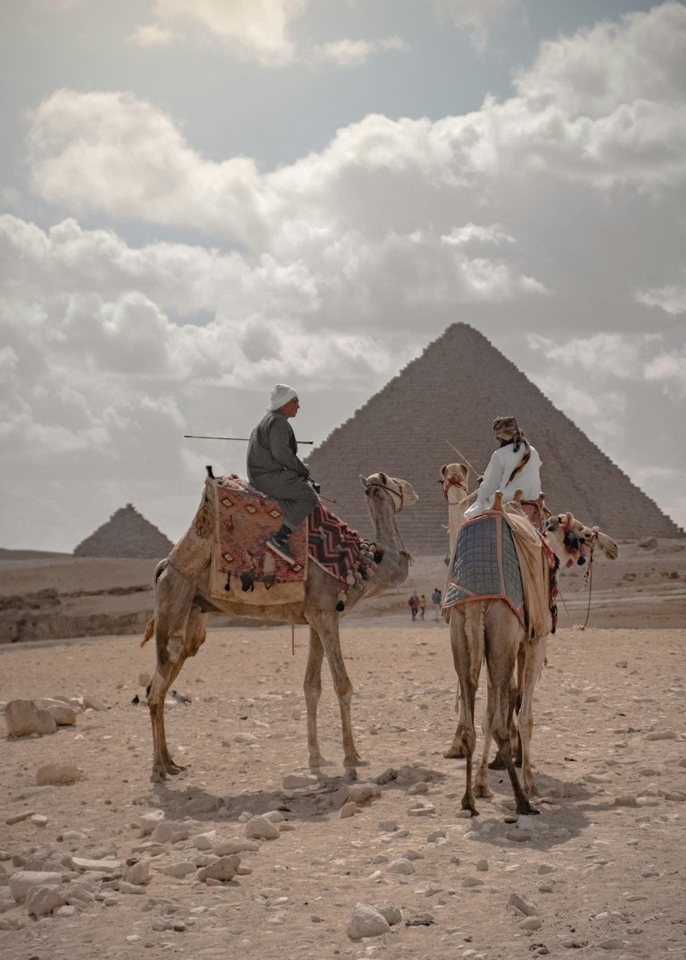 two men riding on camel near oyramid