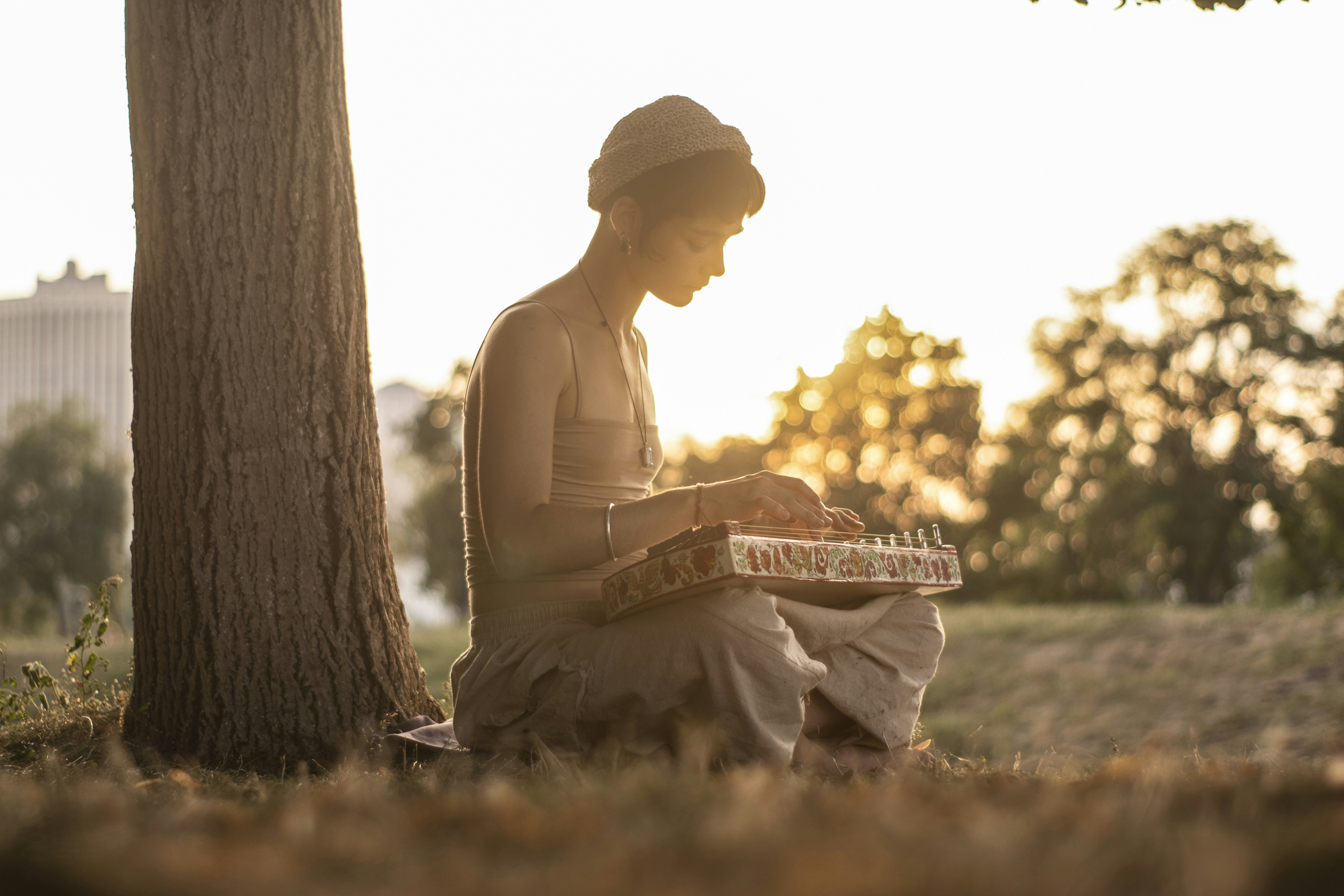 Woman playing instrument by tree