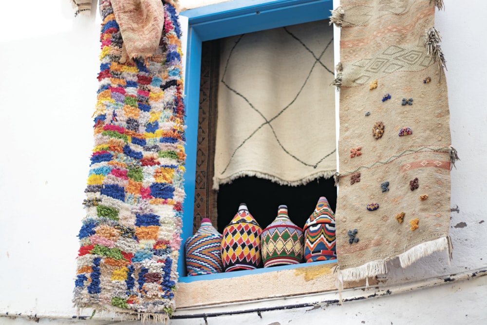 four assorted-color ceramic vases on window frame