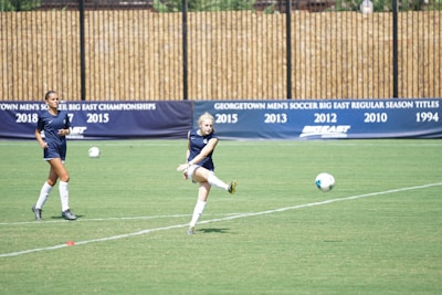 Students playing soccer together on the school field during practice.