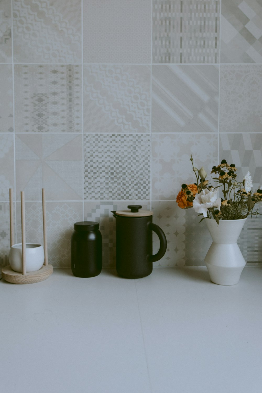 white vase with flowers beside pitcher and jar