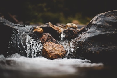 Close-up of crystal-clear water rippling over smooth stones in a quiet creek.