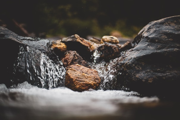 Close-up of crystal-clear spring water flowing over smooth stones.