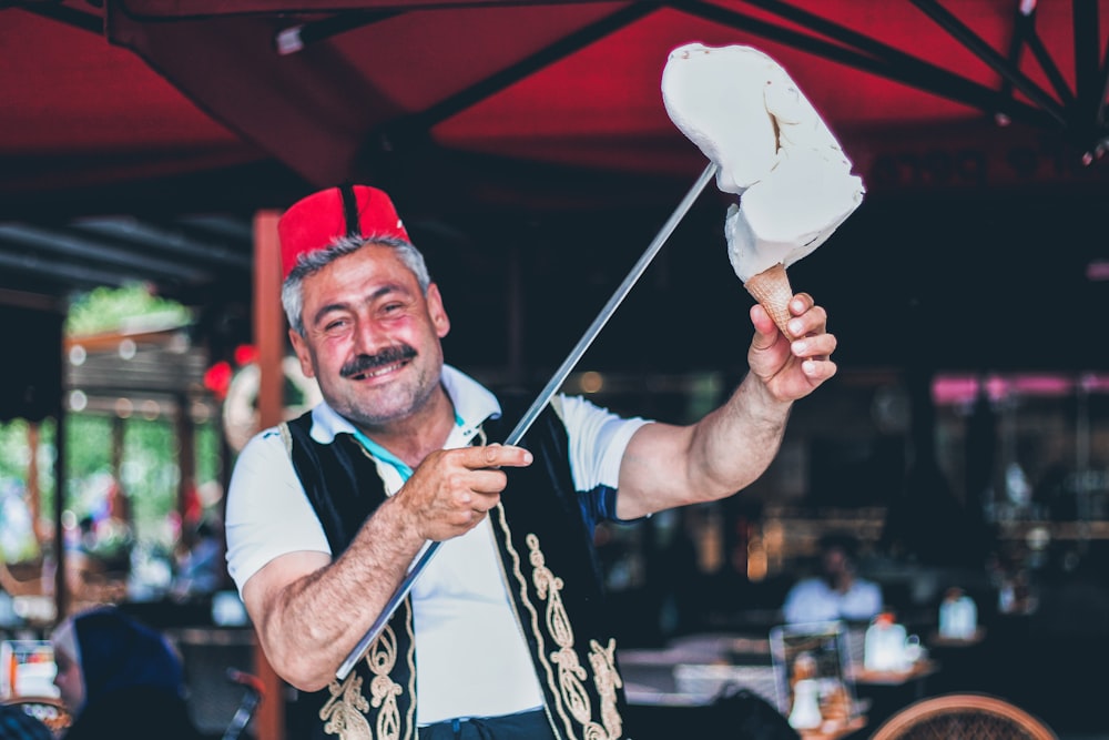 hombre sonriendo y sosteniendo un palo con helado en el cono