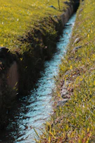 Close-up of water flowing through a modern flood control channel surrounded by vibrant greenery.