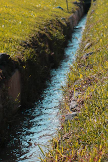 Close-up of water flowing through a modern flood control channel surrounded by vibrant greenery.