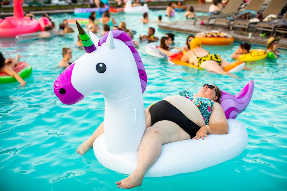 person lying on inflatable unicorn during daytime