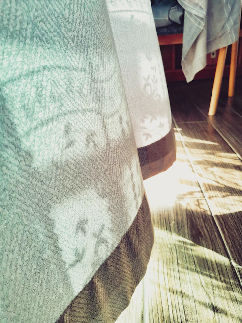 Soft natural light falling on a flowing dress made from recycled silk, draped over a rustic wooden chair