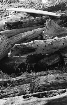 A broken surfboard split in two, laid out on a wooden deck with repair tools.
