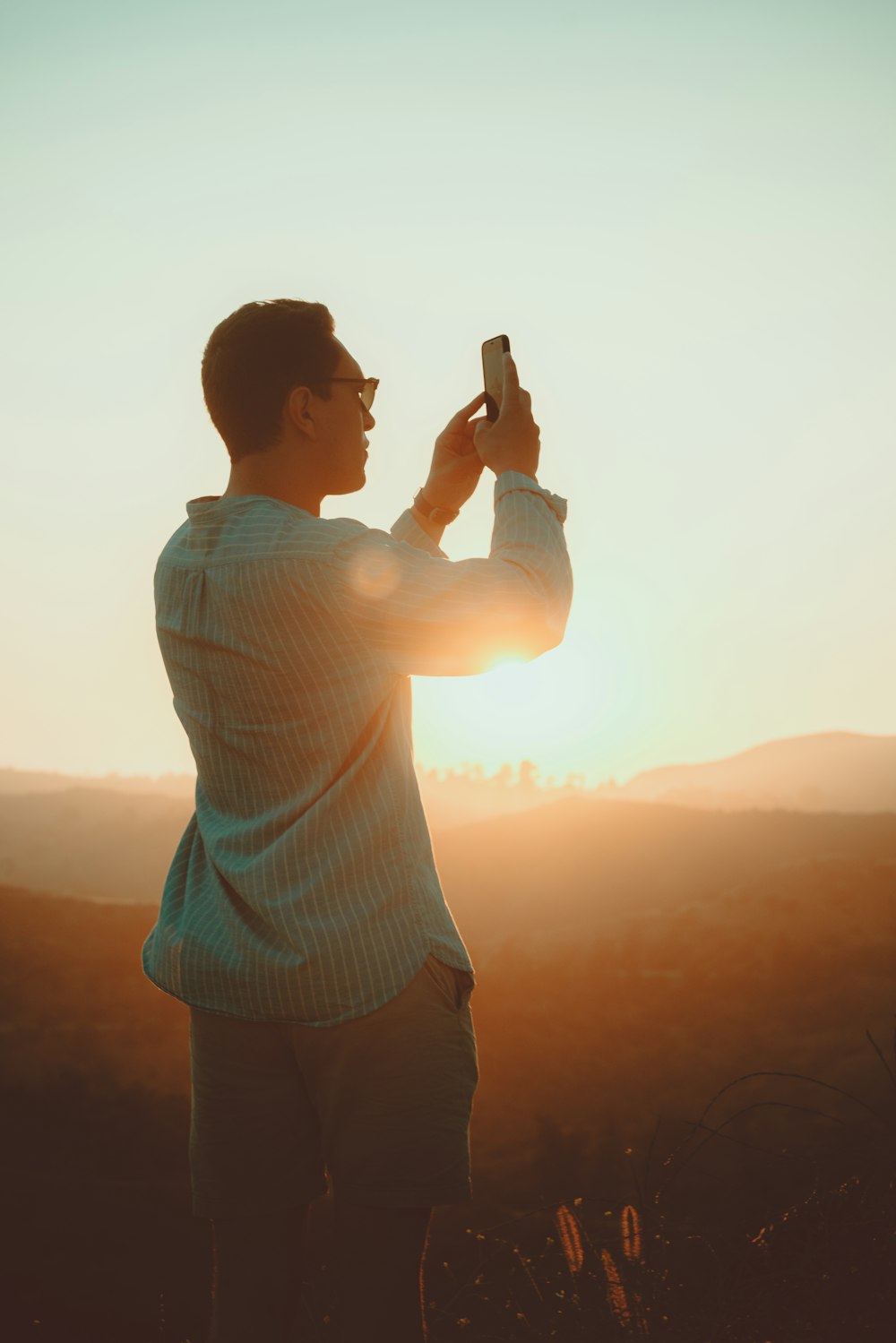 man wearing green dress shirt taking picture during sunset