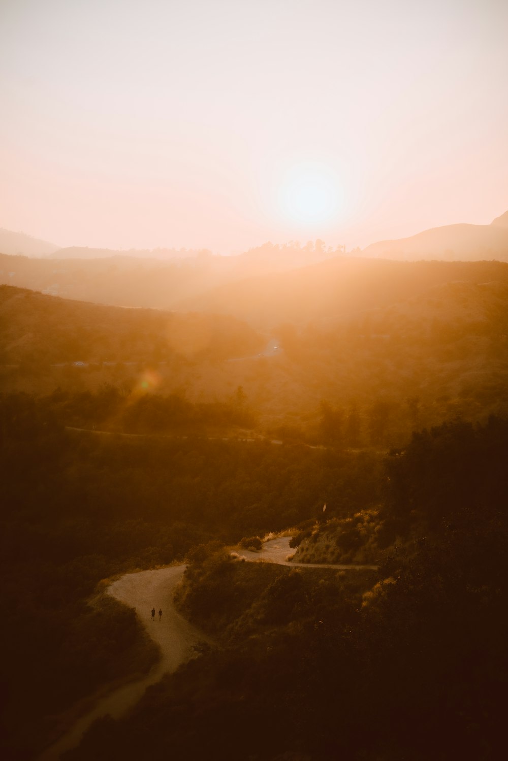 the sun is setting over a hilly area