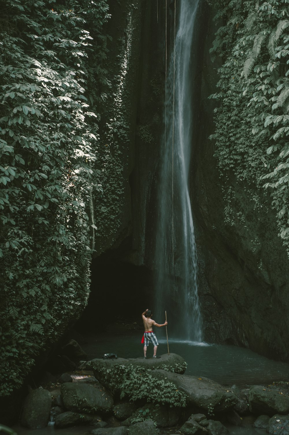 man standing on rock near waterfalls