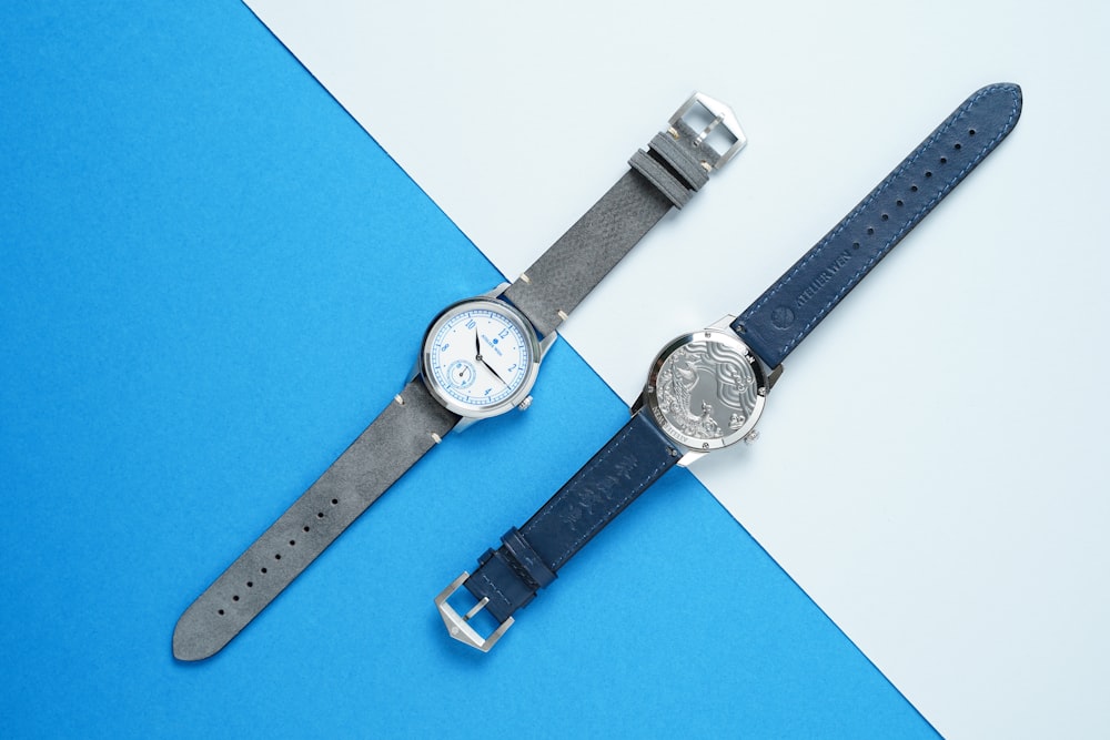 two round silver-colored watches with blue and grey band