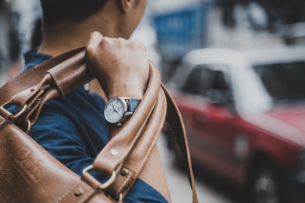 man carrying brown leather bag during daytime