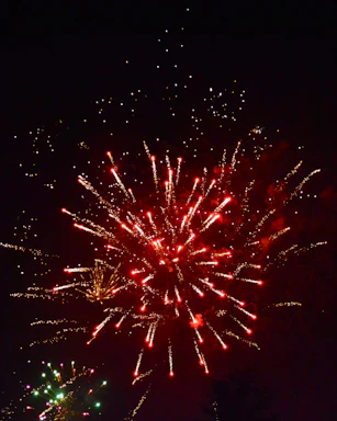 A warm, festive event scene with golden lights and fireworks glowing in the night sky.