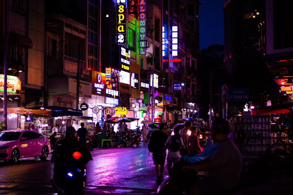 a group of people riding motorcycles down a street at night