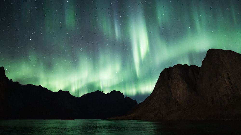 a green and purple aurora over a mountain range