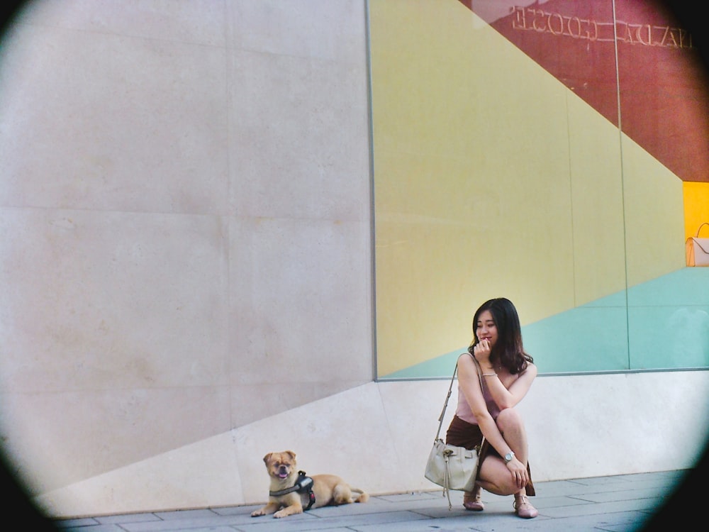 woman sitting near wall beside dog