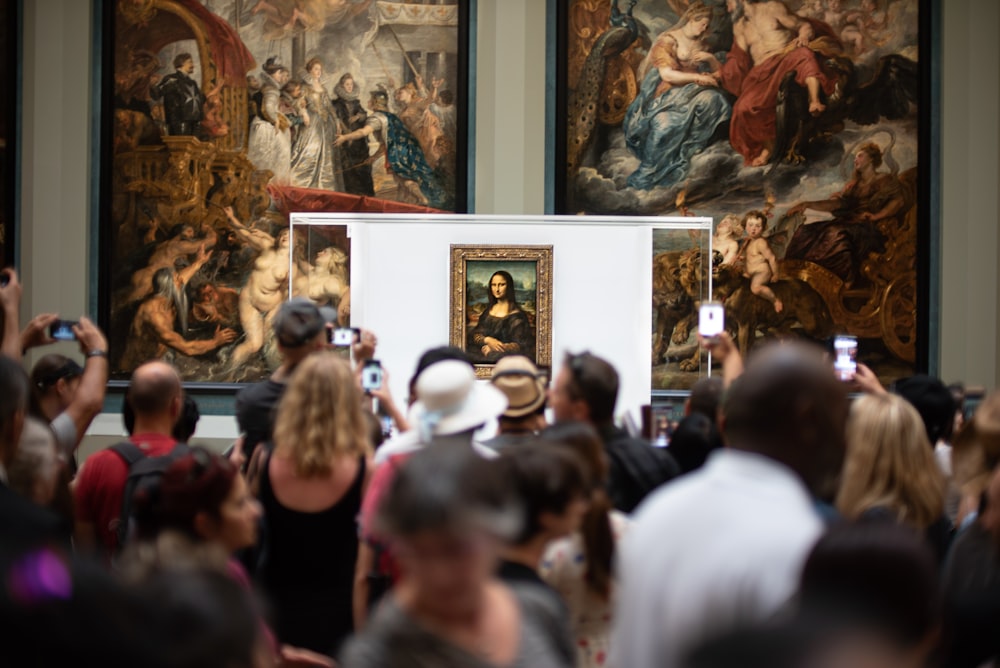 people gathering inside museum talking photo of Mona Lisa painting