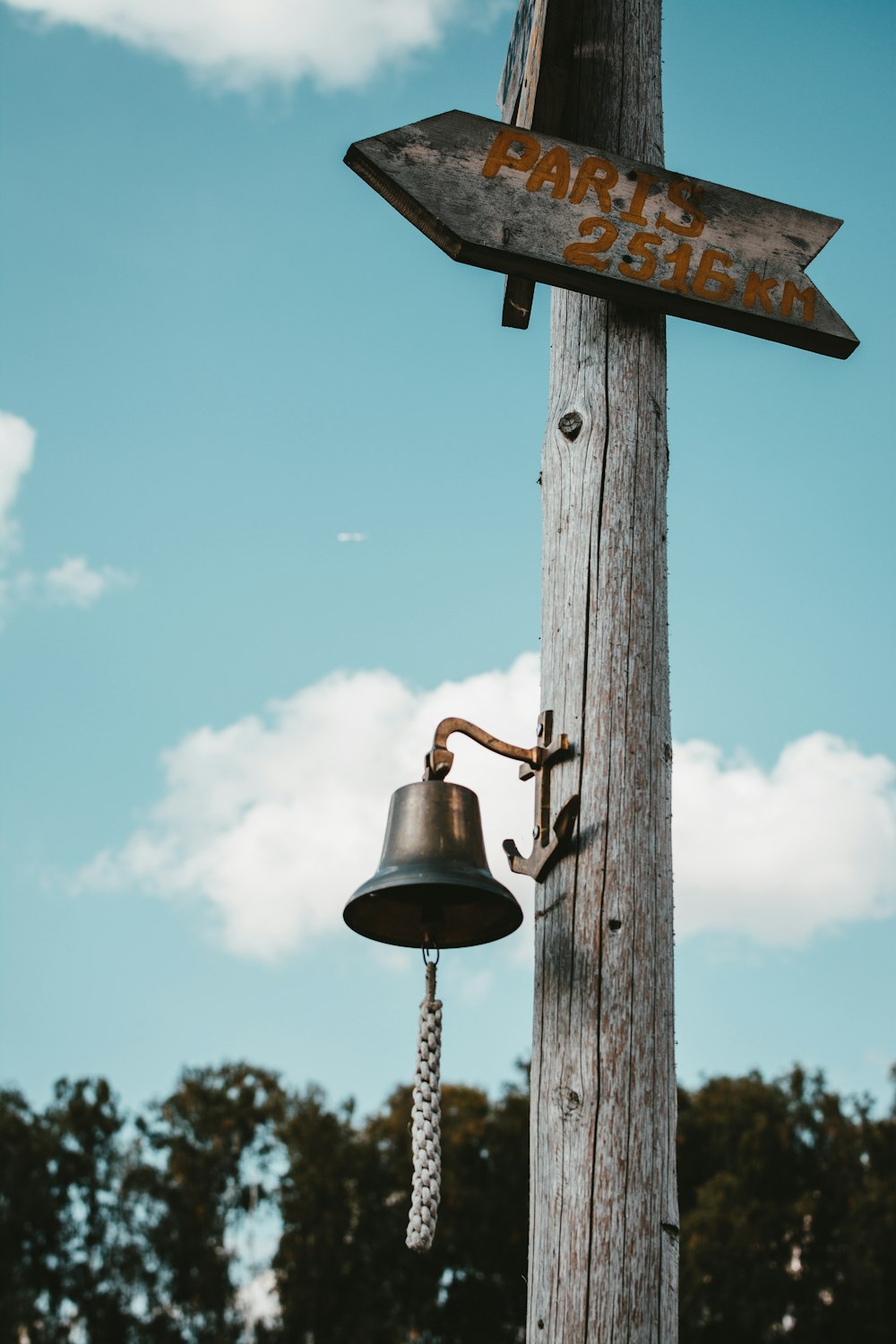 gray metal bell on post at daytime