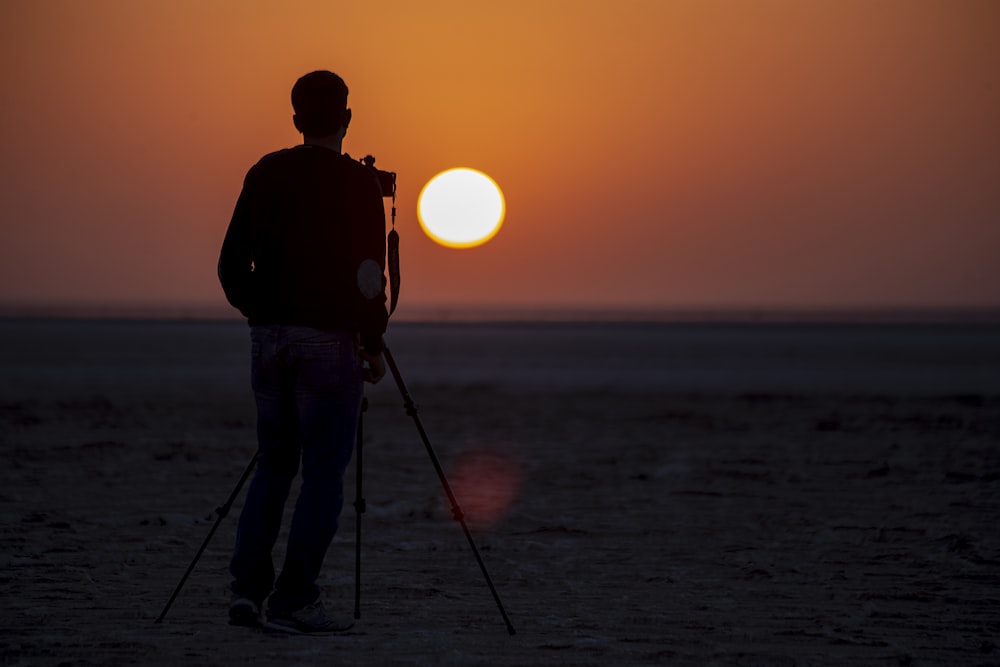 silhouette of man standing beside camera