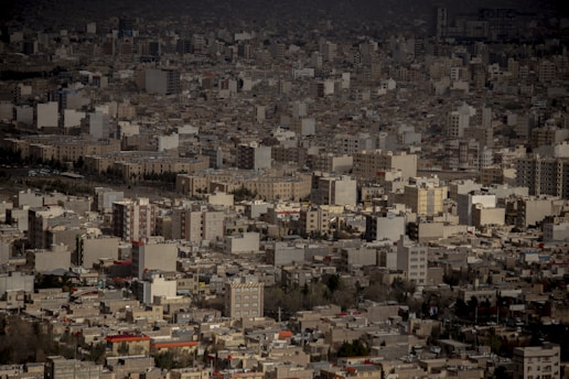 An expansive urban landscape filled with numerous high-rise buildings and apartment blocks. The densely packed architecture suggests a sprawling city scene. The buildings vary in color but mostly consist of beige, gray, and white tones, with some patches of red rooftops.
