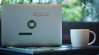 white mug beside laptop