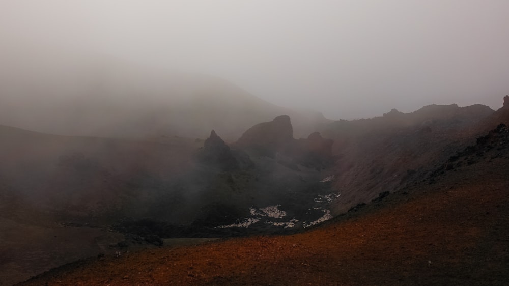 a foggy mountain with a small stream in the foreground