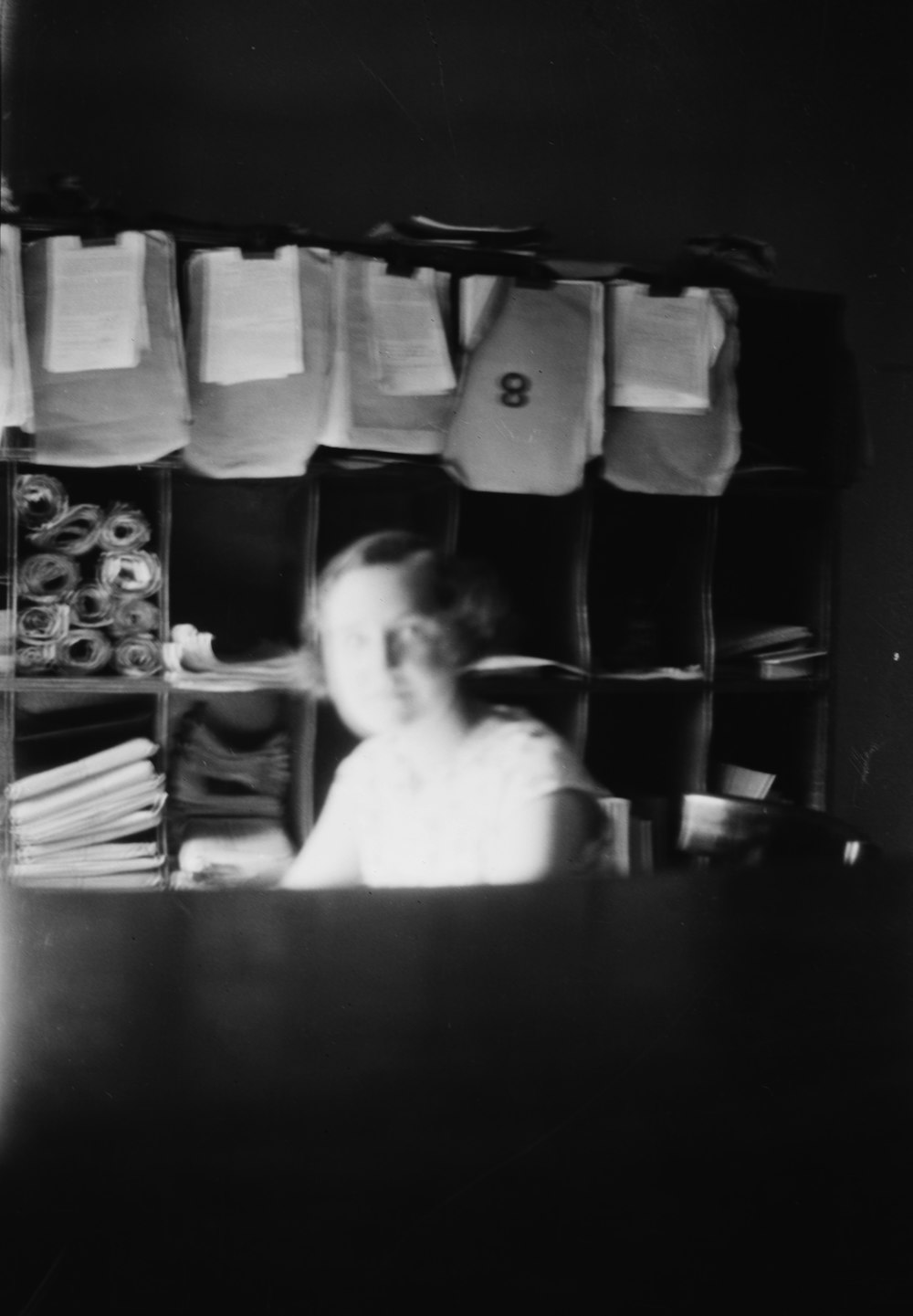 grayscale photo of woman wearing dress sitting on chair looking at table