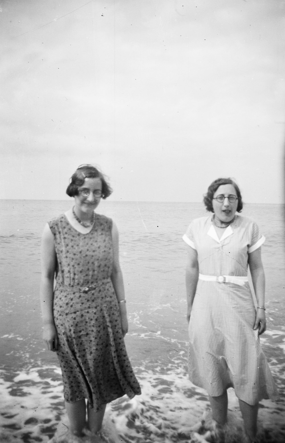 grayscale photography of two women standing in the sea