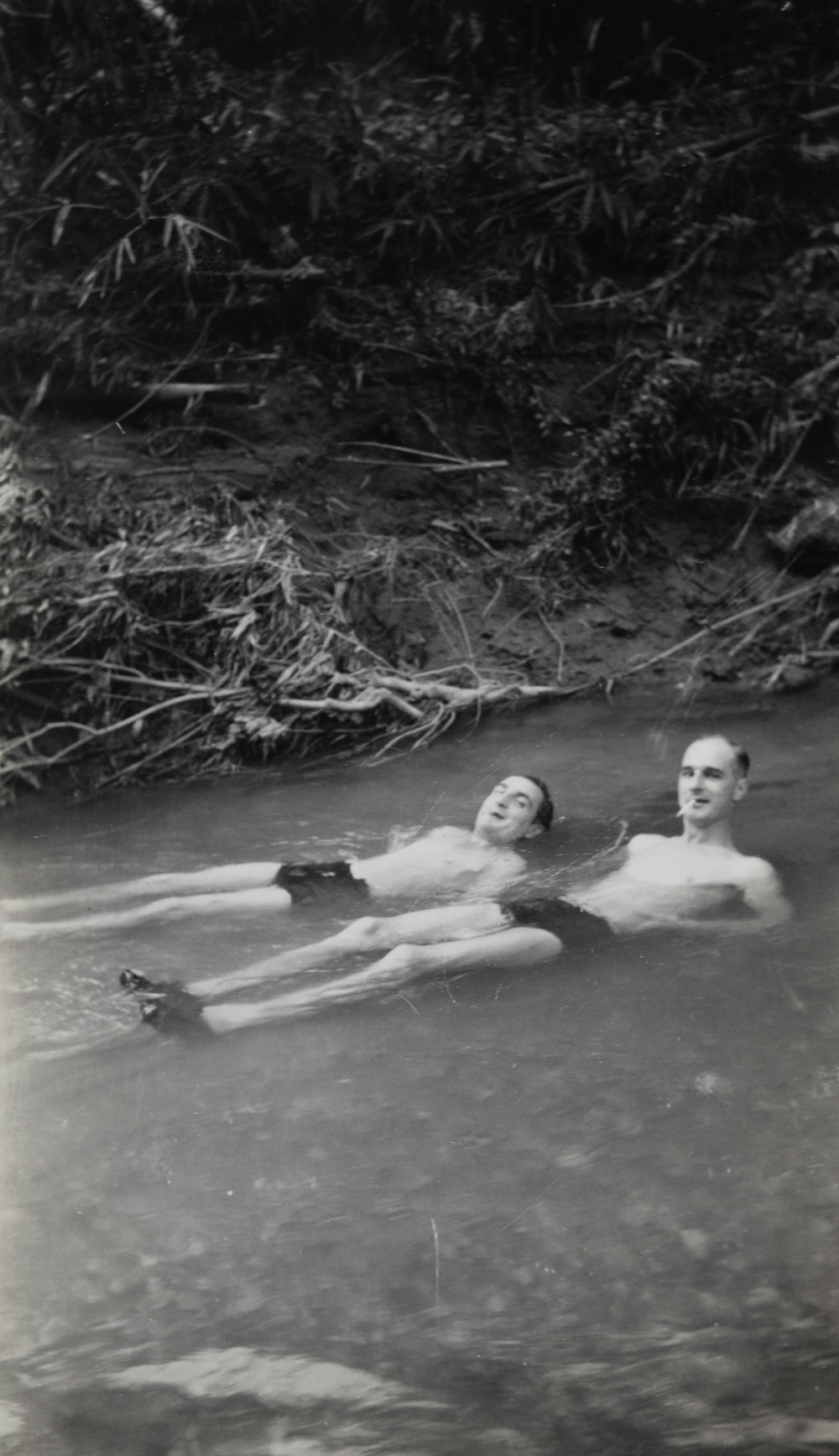 greyscale photo of two men in body o water