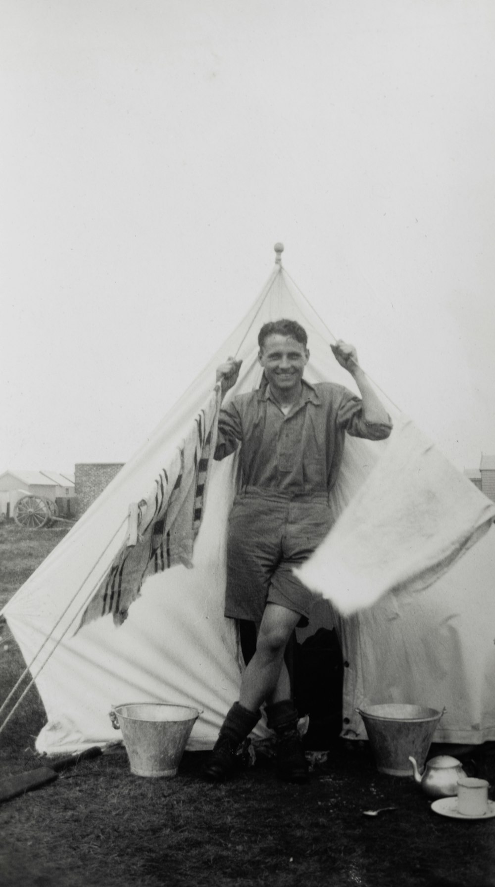 grayscale photo of man standing beside tent